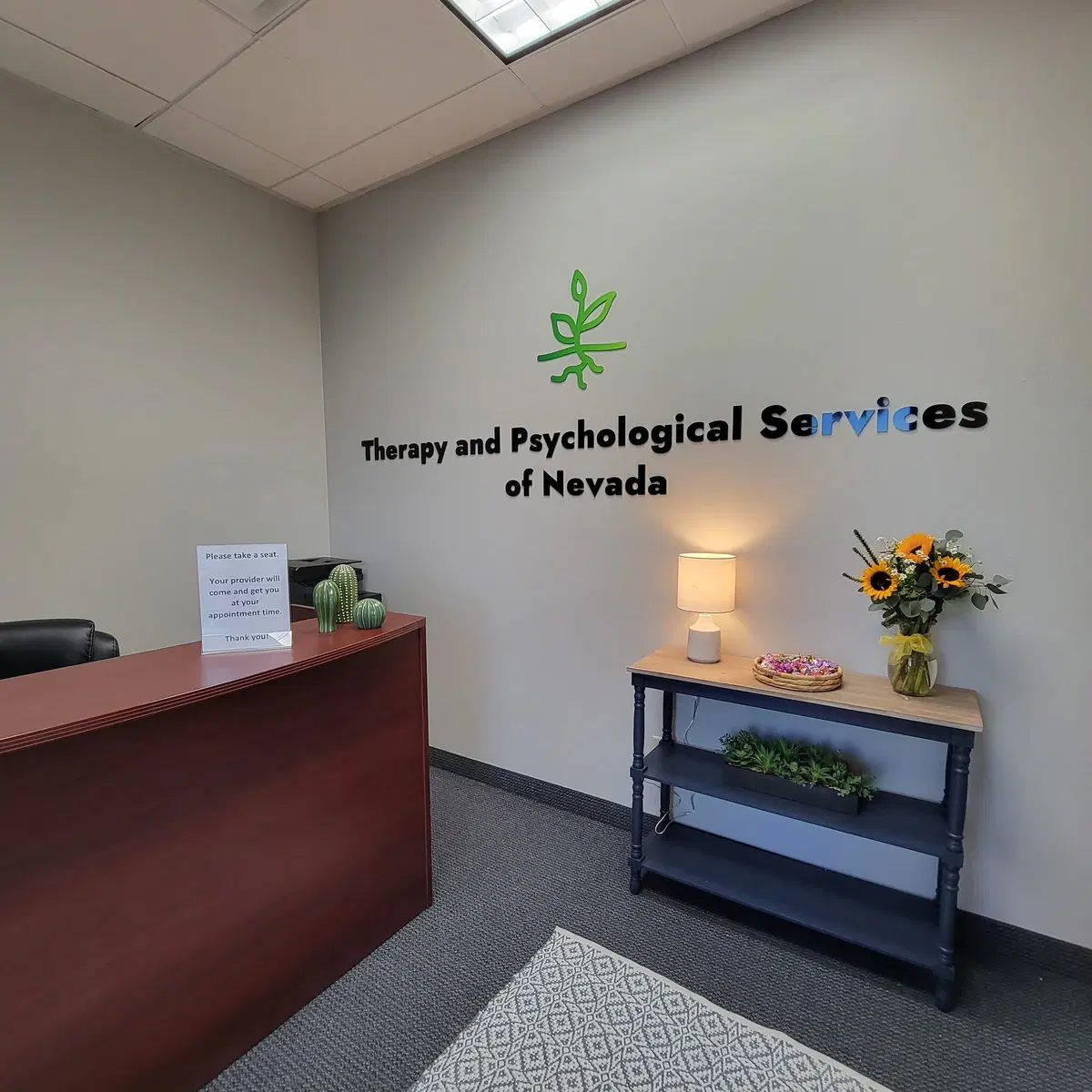 Reception desk beneath the Therapy and Psychological Services of Nevada wall sign.