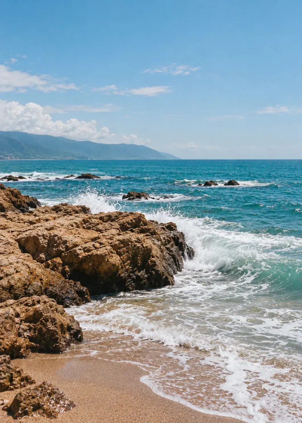 Waves move around rocks along a bright coastline.