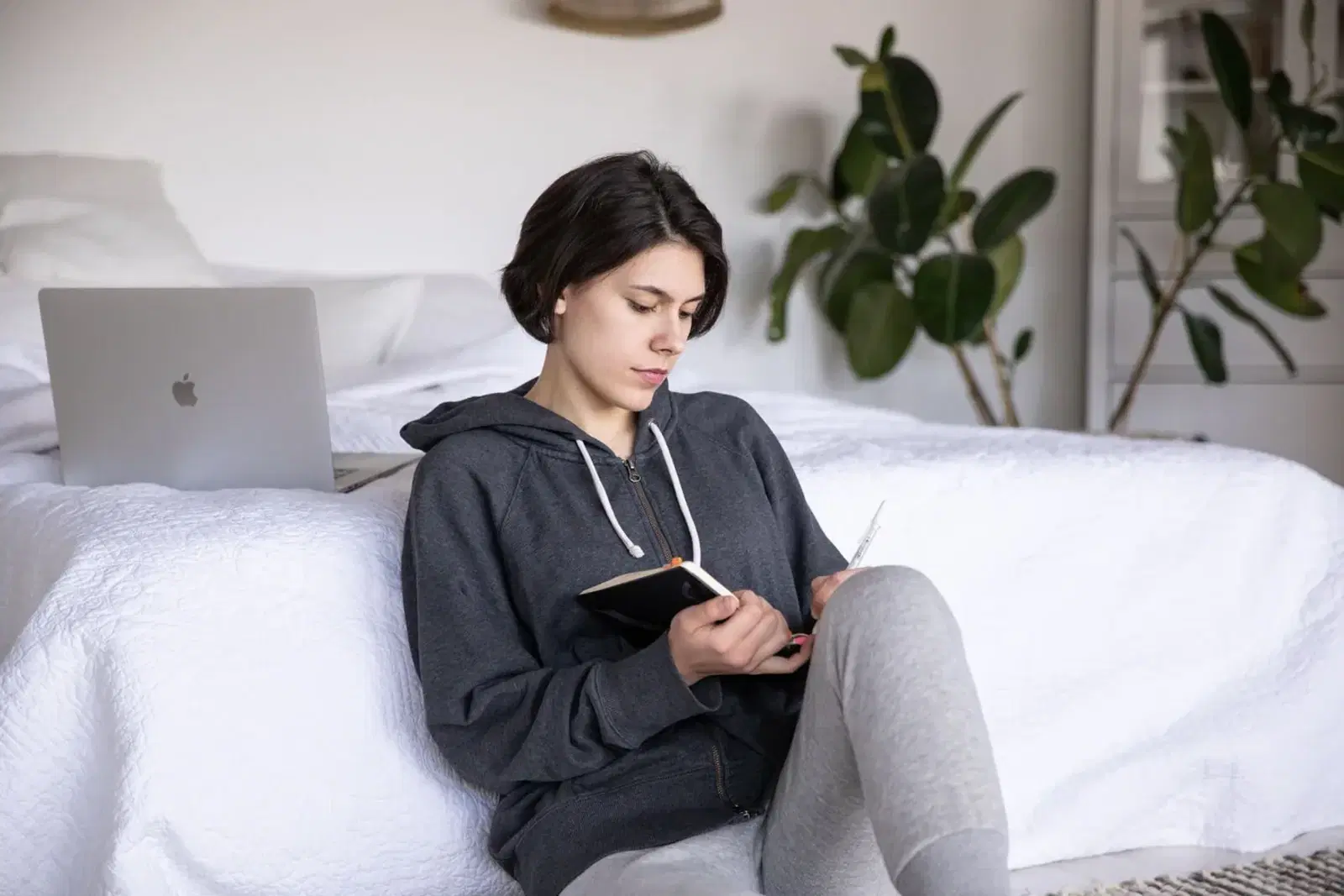 Person writing in a journal while seated on a bed
