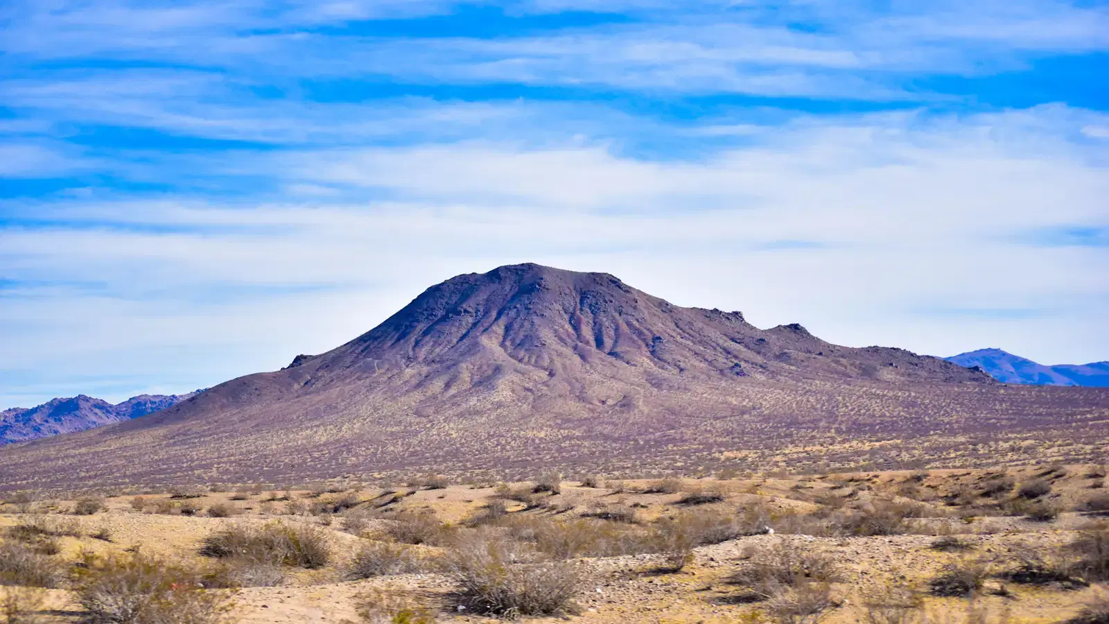 Nevada desert basin with a mountain ridge beneath an open sky.
